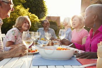 Group Of Senior Friends Enjoying Outdoor Dinner Party At Home