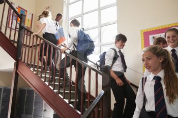 Group Of Teenage Students In Uniform Walking Between Classrooms