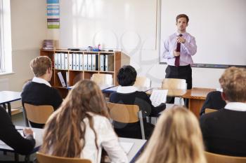 Teenage Students Listening To Male Teacher In Classroom