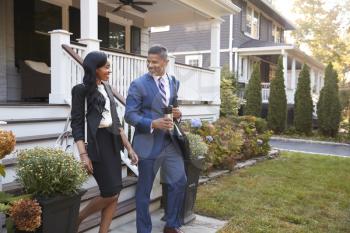 Business Couple Leaving Suburban House For Commute To Work