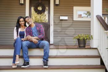 Couple Sitting On Steps Leading Up To Porch Of Home