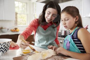 Jewish mother and daughter glazing dough for challah bread