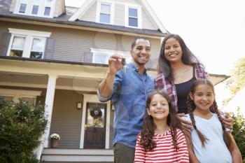 Portrait Of Family Holding Keys To New Home On Moving In Day
