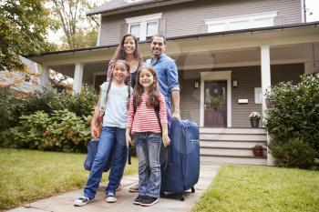 Portrait Of Family With Luggage Leaving House For Vacation