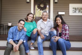 Parents With Adult Offspring Sitting On Steps in Front Of House