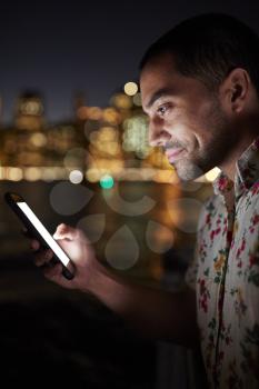 Man Using Mobile Phone At Night With City Skyline In Background