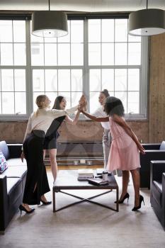 Female colleagues high five at a casual meeting, vertical