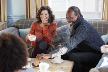 Middle Aged Couple Meeting Friends Around Table In Coffee Shop