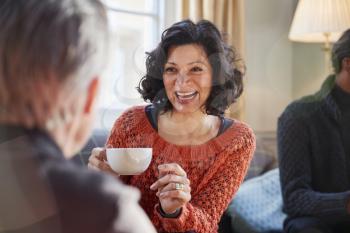 Middle Aged Woman Meeting Friends Around Table In Coffee Shop