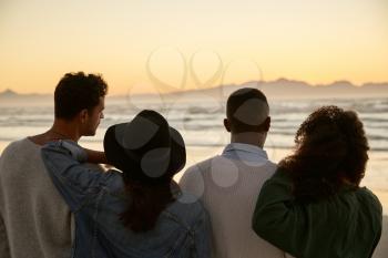Group Of Friends On Winter Beach Watching Sunrise Together