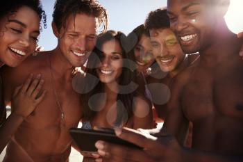 Friends On Beach Vacation Looking At Photo On Mobile Phone