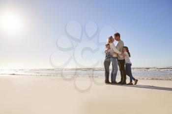 Loving Family Embracing On Winter Beach