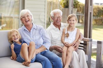 Grandparents With Grandchildren Relaxing On Deck At Home