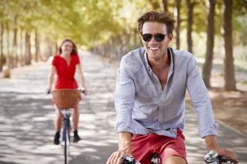Young white adult couple riding bikes on a quiet sunny road
