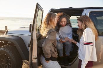 Three girlfriends planning road trip with tablet computer