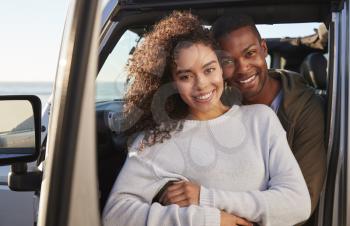 Young mixed race couple embracing by car, close up
