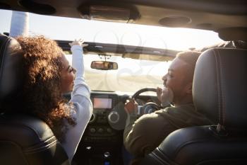 Couple drive looking at each other, rear passenger POV