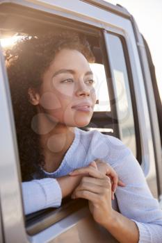 Woman looking out of front passenger car window, vertical