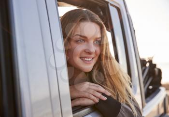 Young woman looking out of open passenger window of a car