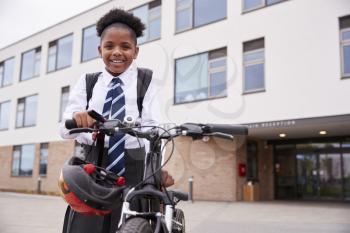 Portrait Of Female High School Student Wearing Uniform With Bicycle Outside School Buildings