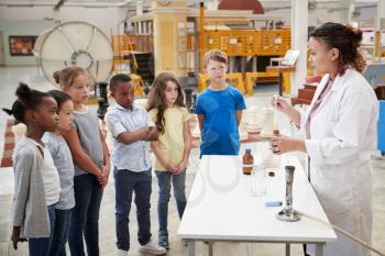Lab technician with group of kids carrying out an experiment