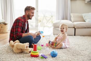 Father and young daughter playing toy instruments at home