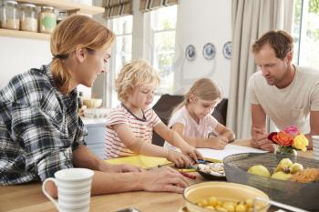 Young white family busy together in their kitchen, close up