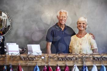 Portrait Of Senior Store Owners Standing Behind Cash Desk