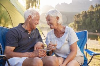 Senior Couple Enjoying Camping Vacation By Lake Making A Toast