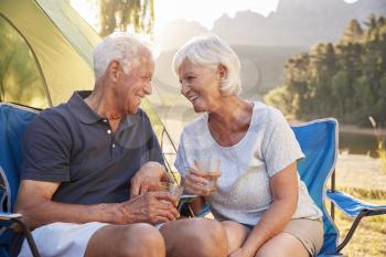 Senior Couple Enjoying Camping Vacation By Lake Making A Toast