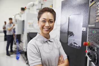 Portrait Of Female Engineer Operating CNC Machinery In Factory