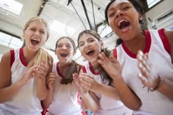 Portrait Of Female High School Basketball Team Celebrating On Court