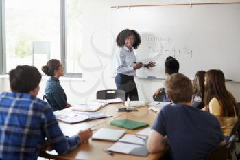 Female High School Tutor At Whiteboard Teaching Maths Class