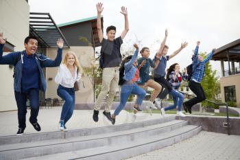 Group Of High School Students Jumping In Air Outside College Buildings