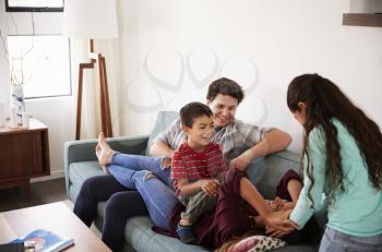 Family Having Fun Lying On Sofa At Home Together