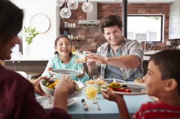 Family Enjoying Meal Around Table At Home Together