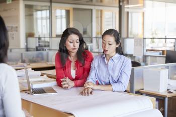 Two female architects studying plans together at work
