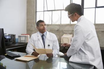 Two male doctors in consultation at desk in office