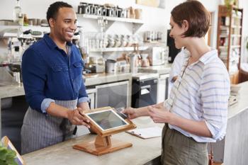 Woman making contactless card payment at a coffee shop