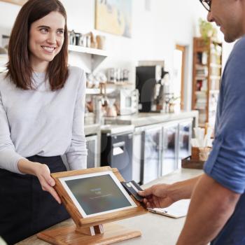 Male customer makes contactless card payment at coffee shop