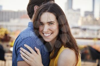 Portrait Of Romantic Couple On Rooftop Terrace With City Skyline In Background