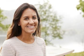 Young mixed race woman smiling to camera in a park, close up