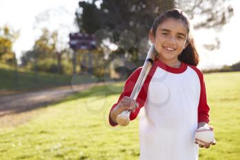 Young Hispanic girl with baseball and bat smiling to camera