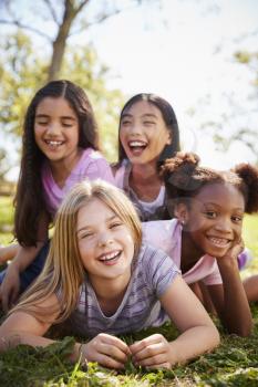 Four schoolgirls lying on each other in a field, close up