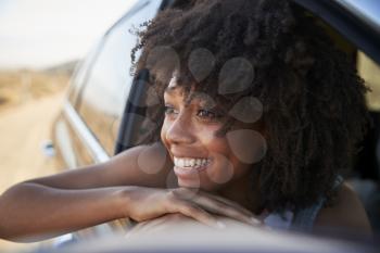 Smiling Woman Looking Out Of Car Window Enjoying Road Trip