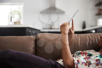 Close Up Of Woman Lying On Sofa At Home Using Digital Tablet