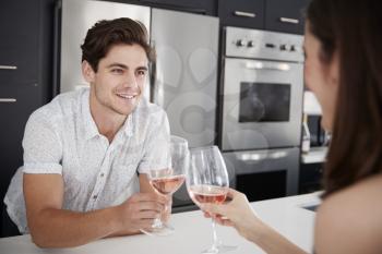 Couple Making Toast As They Drink Wine At Home Standing By Kitchen Island