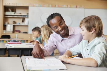 Male elementary school teacher and boy in class, close up