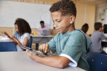 Schoolboy using tablet in elementary school class, close up