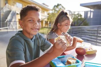Boy at elementary school lunch table smiling to camera